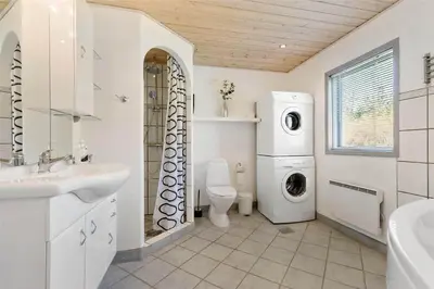 a bathroom with a washing machine and a washer and dryer at BL613-Blokhus-Septimusvej-9 in Blokhus