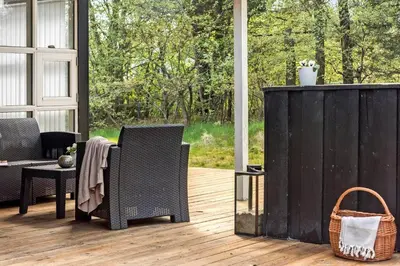 a screened in porch with two chairs and a table at BL1739-Blokhus-Bag-Hojen-47 in Blokhus