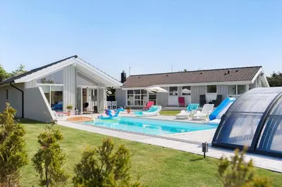 a house with a swimming pool in front of a house at BL1477-Blokhus-Park-Alle-5 in Blokhus