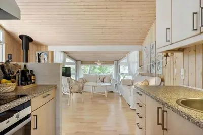 a kitchen with white cabinets and a living room at BL1304-Blokhus-Bag-Hojen-45 in Blokhus