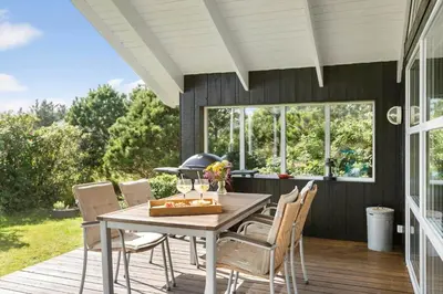 a patio with a table and chairs on a deck at BL935-Blokhus-Tobaksvej-1 in Blokhus
