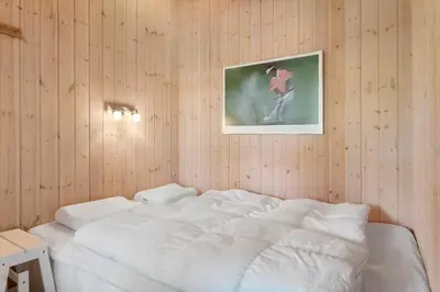 a bedroom with a white bed with a picture on the wall at BL935-Blokhus-Tobaksvej-1 in Blokhus