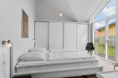 a white bedroom with a bed and a large window at BL234-Blokhus-Sdr-Strandvej-9-A in Blokhus