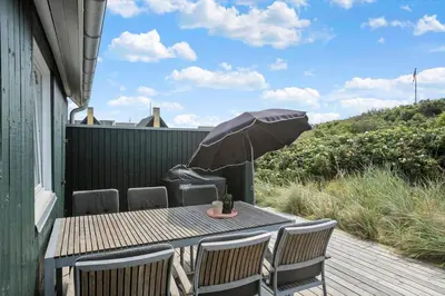 a table and chairs with an umbrella on a deck at BL1580-Saltum-Kohlsvej-17 in Saltum