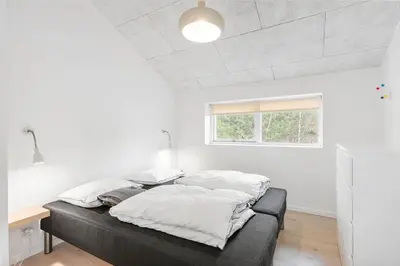 a bedroom with a bed with white sheets and a window at BL1367-Blokhus-Saetergaardsstien-12 in Blokhus