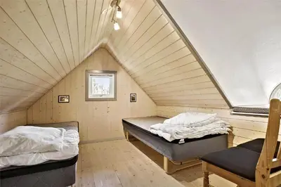 a room with two beds and a chair in a attic at BL238-Pandrup-Fyrregangen-18 in Pandrup