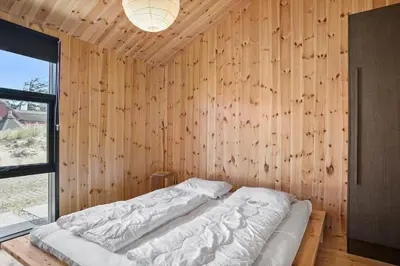 a bedroom with a bed in a wooden wall at BL1436-Blokhus-Mollevej-13 in Blokhus