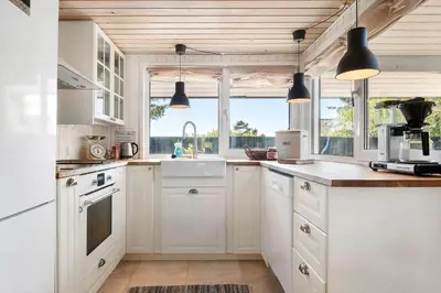 a kitchen with white cabinets and a large window at BL1211-Blokhus-Carl-Nielsensvej-3 in Blokhus