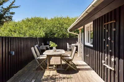 a wooden deck with a table and chairs on it at BL1211-Blokhus-Carl-Nielsensvej-3 in Blokhus