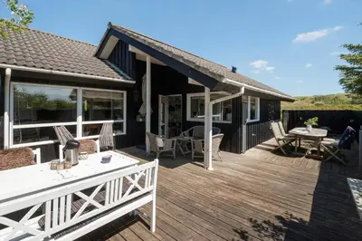 a wooden deck with a table and chairs on it at BL1211-Blokhus-Carl-Nielsensvej-3 in Blokhus