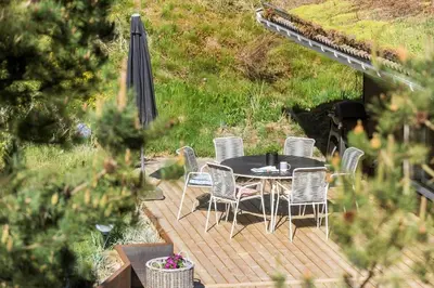 a table and chairs on a deck with an umbrella at BL1585-Blokhus-Bregnehojvej-1 in Blokhus