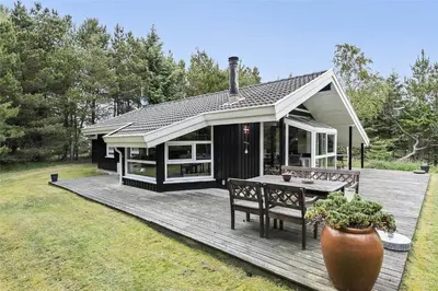 a house with a deck with a table and benches at BL1186-Blokhus-Morten-Nielsensvej-84 in Blokhus