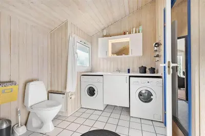 a bathroom with a washing machine and a toilet at BL1186-Blokhus-Morten-Nielsensvej-84 in Blokhus