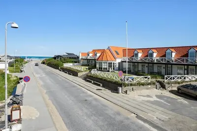 an empty street with houses and the ocean in the background at BL1584-Blokhus-Strandvejen-14-Lejl-4 in Blokhus