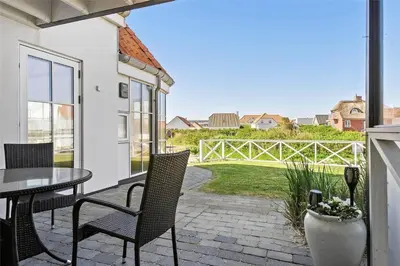 a patio with a table and chairs and a view of a yard at BL1584-Blokhus-Strandvejen-14-Lejl-4 in Blokhus