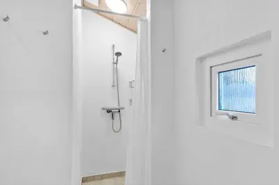 a shower in a white bathroom with a window at BL1790-Blokhus-Jens-Baerentsvej-28 in Blokhus