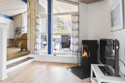 a living room with a fireplace in front of a window at BL1720-Saltum-Kvansletten-27 in Saltum