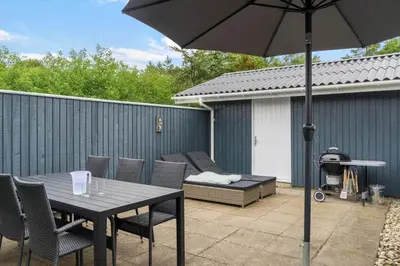 a patio with a table and chairs and an umbrella at BL1487-Saltum-Brune-Banke-7 in Saltum