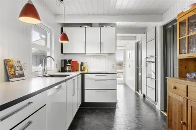 a kitchen with white cabinets and a black counter top at BL1455-Blokhus-Pirupshvarrekrogen-6 in Blokhus