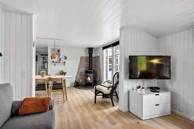 a living room with a tv and a dining room with a table at BL1632-Blokhus-Klintevej-14 in Blokhus