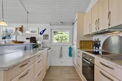 a kitchen with wooden cabinets and a window at BL317-Saltum-Kalundborgvej-1 in Saltum