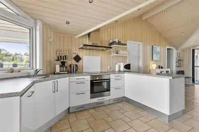 a kitchen with white cabinets and a large window at BL1139-Blokhus-Sletten-3 in Blokhus