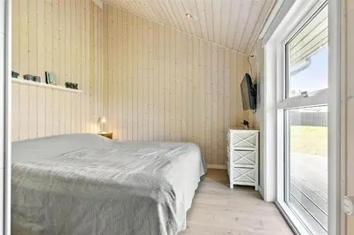 a bedroom with a bed and a large window at BL1139-Blokhus-Sletten-3 in Blokhus