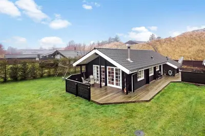 a small house with a deck on a lawn at BL1788-Blokhus-Gyvelvej-21 in Blokhus