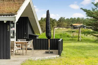 a black house with a table and a black umbrella at BL177-Saltum-Kvansletten-23 in Saltum