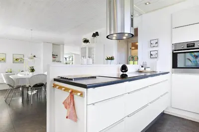 a kitchen with white cabinets and a dining room at BL374-Blokhus-Vagerfedet-10 in Blokhus