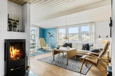 a living room with a fireplace and a couch at BL374-Blokhus-Vagerfedet-10 in Blokhus