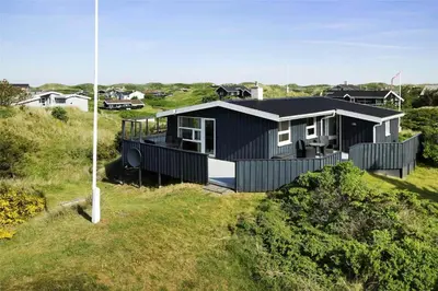 a black house on top of a grassy hill at BL374-Blokhus-Vagerfedet-10 in Blokhus
