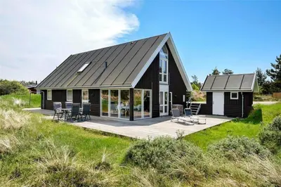 a black house with a deck and chairs at BL1362-Saltum-Kronhjortvej-19 in Saltum