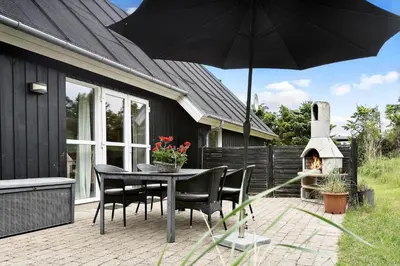 a patio with a table and chairs and an umbrella at BL381-Blokhus-Maxvej-4 in Blokhus