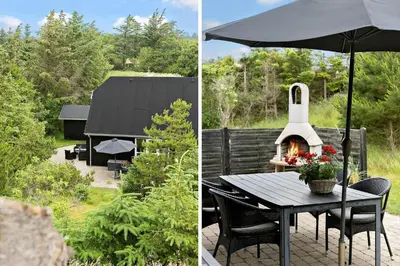 a patio with a table with an umbrella and a fireplace at BL381-Blokhus-Maxvej-4 in Blokhus