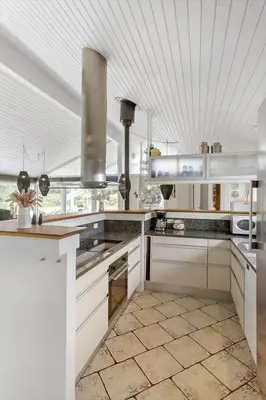 a kitchen with white cabinets and a tile floor at BL1418-Blokhus-Malinsvej-14 in Blokhus
