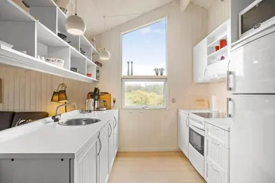 a kitchen with white cabinets and a large window at BL1558-Saltum-Opossumvej-20 in Saltum