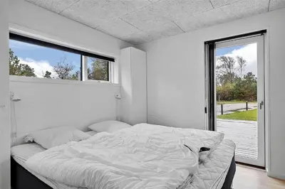 a white bedroom with a large bed and a window at BL1442-Blokhus-Bag-Hojen-43 in Blokhus