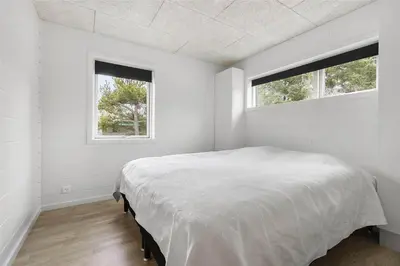 a white bedroom with a bed and two windows at BL1442-Blokhus-Bag-Hojen-43 in Blokhus