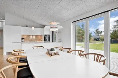 a white kitchen with a large white table and chairs at BL1442-Blokhus-Bag-Hojen-43 in Blokhus