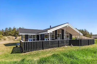a house with a wooden fence in the grass at BL1751-Blokhus-Wolundsvej-4-A in Blokhus
