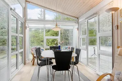 a dining room with windows and a table and chairs at BL1213-Pandrup-Rodhusparken-14 in Pandrup