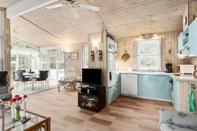 a kitchen with a refrigerator and a table with a tv at BL1213-Pandrup-Rodhusparken-14 in Pandrup