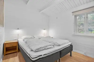 a white bedroom with a bed and a window at BL554-Blokhus-Kragebak-2 in Blokhus