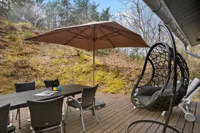 a patio with a table and a swing and an umbrella at BL554-Blokhus-Kragebak-2 in Blokhus
