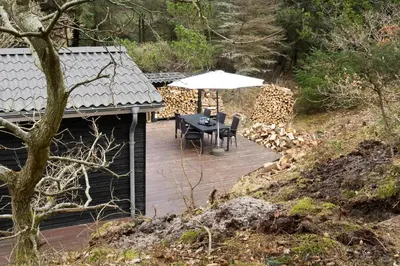 a wooden deck with a table and an umbrella at BL554-Blokhus-Kragebak-2 in Blokhus