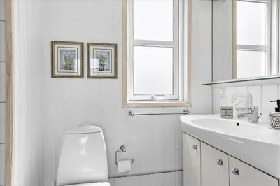 a white bathroom with a toilet and a sink at BL362-Blokhus-Klitvejen-42 in Blokhus
