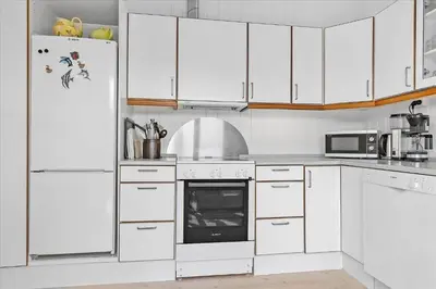 a white kitchen with white cabinets and a refrigerator at BL362-Blokhus-Klitvejen-42 in Blokhus