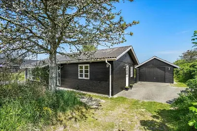 a house with a garage next to a driveway at BL220-Blokhus-Bakkevaenget-9 in Blokhus