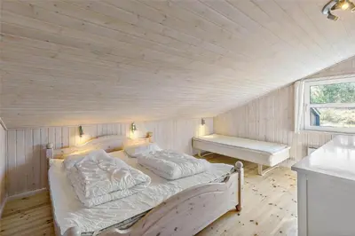 a bed in a room with a wooden ceiling at BL464-Blokhus-Blaabaerskraenten-8 in Blokhus
